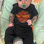 Kagen joined the competition — help win amazing prizes! baby, infant, pacifier, black_clothing, harley_davidson, tattoo_sleeves, baby_chair, colorful_background, blue_eyes, socks, cute, portrait, indoor, child, young_baby, seated, fabric, pattern, toy_design, playful