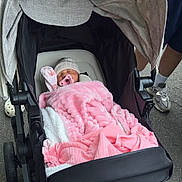 Maiya is registered to the contest to win money with this photo: baby, blanket, stroller, pacifier, hat, sleeping, person, footwear, shoe, sock, outdoor, pavement, clothing, hand, wheel, fabric, infant, resting, parent, transport