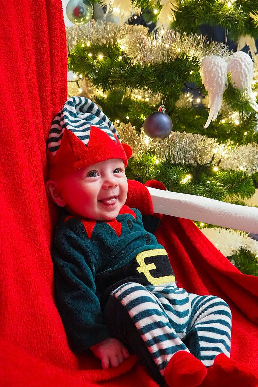 Tinaël participe au concours pour gagner de l'argent avec cette photo : baby, baby_toddler_clothing, cap, child, christmas_eve, christmas_ornament, christmas_tree, event, fun, grass, happy, headwear, holiday, holiday_ornament, leisure, people_in_nature, person, plant, smile, toddler