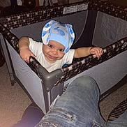 Aiko is registered to the contest to win money with this photo: baby, child, playpen, hat, blue_hat, smile, indoor, carpet, person, jeans, furniture, home, baby_clothes, hand, face, happy, toy, parent, room, floor