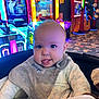 Georges participe au concours pour gagner de l'argent avec cette photo : amusement, arcade, arcade_machine, baby, bib, carpet, child, closeup, colorful, gaming, indoor, infant, neon_lights, onesie, play_area, portrait, seat, smile, stuffed_toy, tongue_out