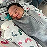 newborn, baby, infant, sleeping, swaddled, blanket, hospital, medical_tube, feeding_tube, footprint_pattern, bed, crib, cute, face, peaceful, child, healthcare, resting, indoors, person