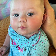 Kaisley joined the competition — help win amazing prizes! baby, child, infant, blue_clothing, polka_dot, onesie, hand, face, eyes, cheeks, sitting, indoor, soft_texture, pink_hearts, cute, portrait, person, support, toddler, closeup