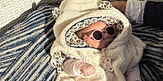 Ambre a rejoint le concours — aidez-le/la à gagner de superbes lots ! baby, child, sunglasses, hooded_blanket, fluffy_clothing, striped_cushion, wicker_chair, shadow, hand, outdoor, sunlight, patterned_socks, leopard_print, relaxed, cute, infant, cozy, person, fashion, accessory
