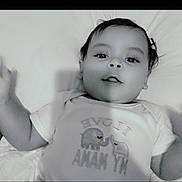 Kayden is registered to the contest to win money with this photo: baby, infant, child, onesie, elephant, bedding, pillow, lying_down, portrait, black_and_white, smile, face, eyes, hair, arm, hand, toddler, cute, clothing, mouth