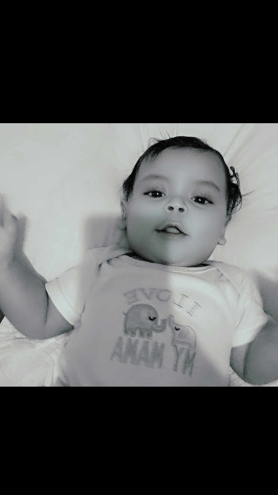 Kayden is registered to the contest to win money with this photo: baby, infant, child, onesie, elephant, bedding, pillow, lying_down, portrait, black_and_white, smile, face, eyes, hair, arm, hand, toddler, cute, clothing, mouth