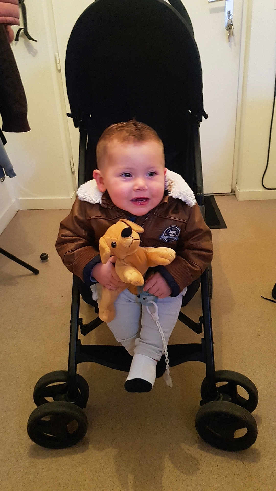 Stan Pillon participe au concours pour gagner de l'argent avec cette photo : toddler, child, stroller, plush_toy, dog_toy, jacket, pacifier, indoor, carpet, door, keys, person, clothing, wheel, baby, cute, seated, face, happy, hand