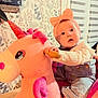 Esmée participe au concours pour gagner de l'argent avec cette photo : baby, infant, child, unicorn_plush, plush_toy, ride_on_toy, headband, bow, pink, overalls, denim, sitting, holding, handle, surprised_expression, wide_eyes, indoor, wallpaper, window_blinds, cute