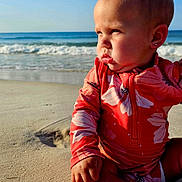 Ella is registered to the contest to win money with this photo: baby, beach, child, cute, earring, floral_pattern, nature, ocean, outdoor, portrait, sand, sitting, sky, summer, sunlight, sunny, swimsuit, vacation, water, waves