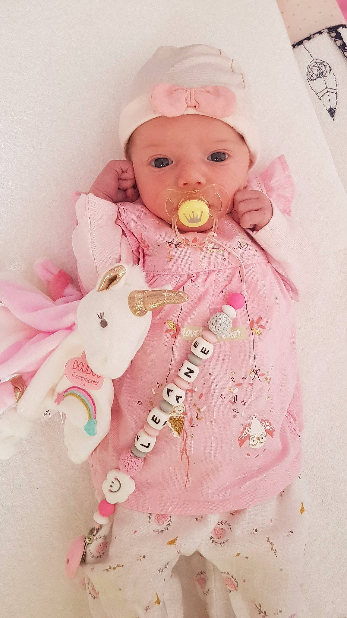 Léane participe au concours pour gagner de l'argent avec cette photo : baby, baby_products, baby_safety, baby_toddler_clothing, baby_toys, cheek, child, doll, dress, embellishment, headwear, linens, magenta, pattern, peach, person, petal, pink, skin, sleeve