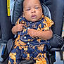 baby, child, car_seat, clothing, patterned_outfit, blue_socks, infant, seatbelt, black_car_seat, cute, portrait, person, indoor, expression, hands, footwear, young_child, sitting, face, young_baby