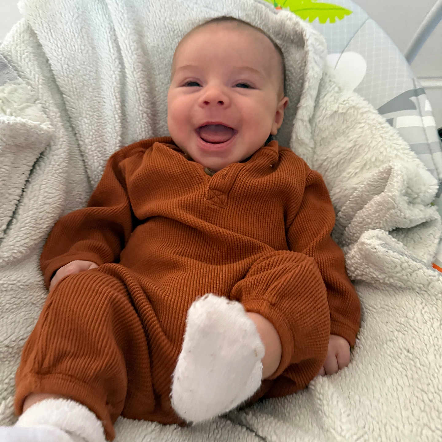 Callen joined the competition — help win amazing prizes! baby, bouncer, brown_onesie, cheeks, close_up, cozy, face, grin, happy, infant, newborn, nursery, portrait, seat, smile, sock, soft_texture, tongue_out, toy, white_blanket