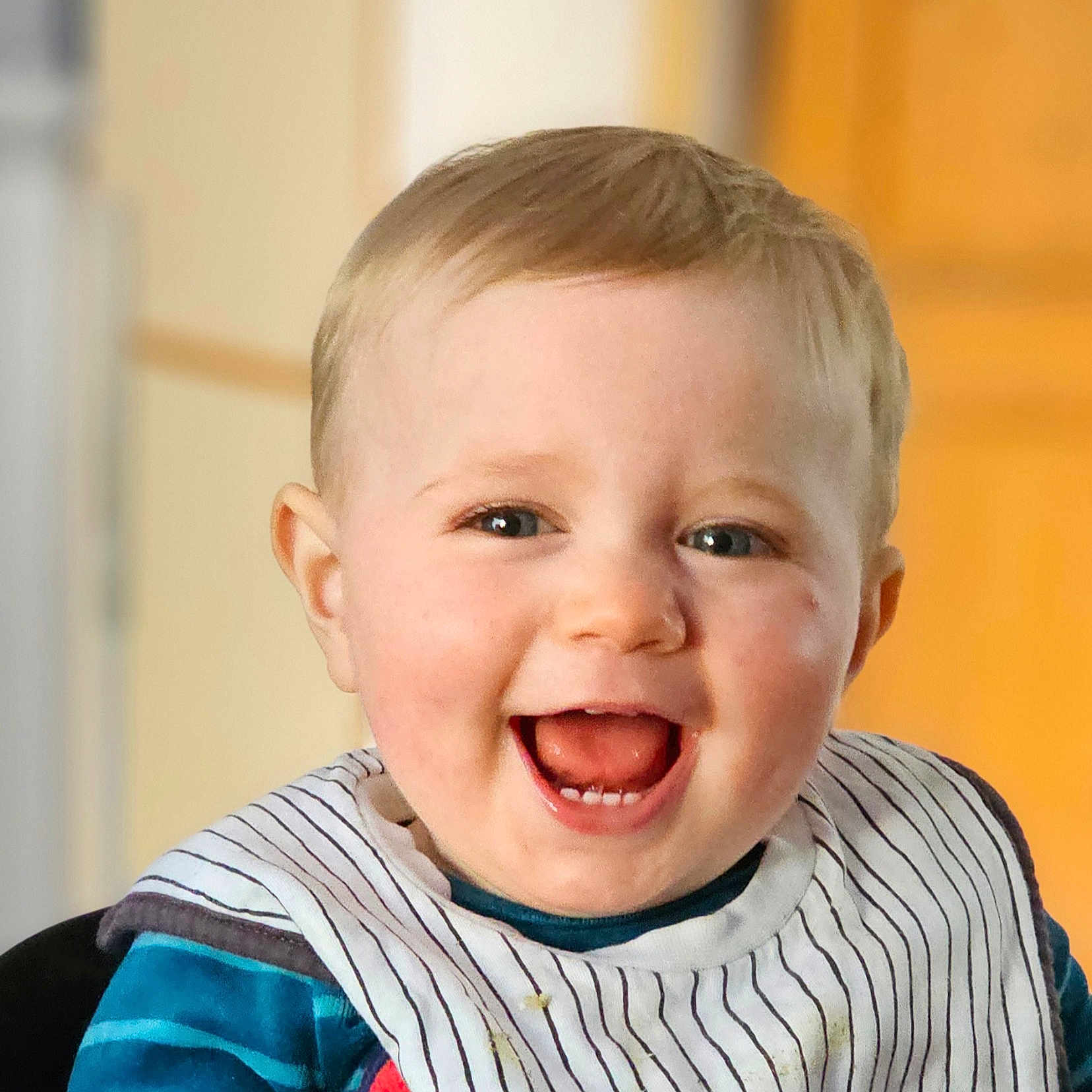 Gabriel participe au concours pour gagner de l'argent avec cette photo : baby, background_blur, bib, blue_clothing, cheerful, child, clothing, cute, face, happy, head, indoor, person, portrait, sitting, skin, smiling, striped, teeth, young_child