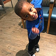 Aiden is registered to the contest to win money with this photo: child, boy, blue_shirt, black_pants, sneakers, indoor, wooden_floor, chair, shadow, smile, playful, pose, happy, young, person, flooring, casual, furniture, head, eyes