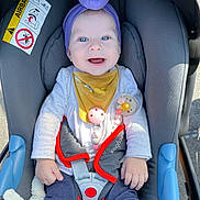 Ruth joined the competition — help win amazing prizes! baby, child, car_seat, purple_headband, pacifier_clip, smiling, blue_eyes, white_shirt, yellow_bib, gray_cushion, safety_harness, toy, outdoor, daylight, infant, cute, happy, casual_clothing, toddler, seatbelt