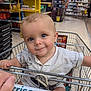 aisle, baby, blue_eyes, child, clothing, cute, food, grocery_store, hand, happy, infant, metal, person, portrait, retail, seat, shopping, shopping_cart, smiling, store