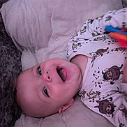Freddie joined the competition — help win amazing prizes! baby, infant, smile, happy, onesie, toy, lying_down, cute, cartoon_print, child, soft_surface, indoor, face, head, hand, playful, young, expression, person, clothing