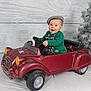 baby, child, toy_car, green_sweater, gray_cap, smiling, indoor, christmas_tree, winter, holiday, festive, playful, portrait, seat, wheel, vehicle, happy, cute, background, decor