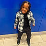 Jahzi is registered to the contest to win money with this photo: child, smiling, braided_hair, plaid_shirt, black_clothing, standing, blue_wall, tile_floor, happy, casual_wear, indoors, person, fashion, portrait, cute, youth, footwear, urban, style, posing