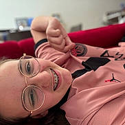 Lylou participe au concours pour gagner de l'argent avec cette photo : child, glasses, braces, smile, red_couch, pink_jersey, sportswear, person, face, portrait, indoor, relaxed, young, happy, casual, clothing, sitting, home, person_wearing_glasses, eyewear