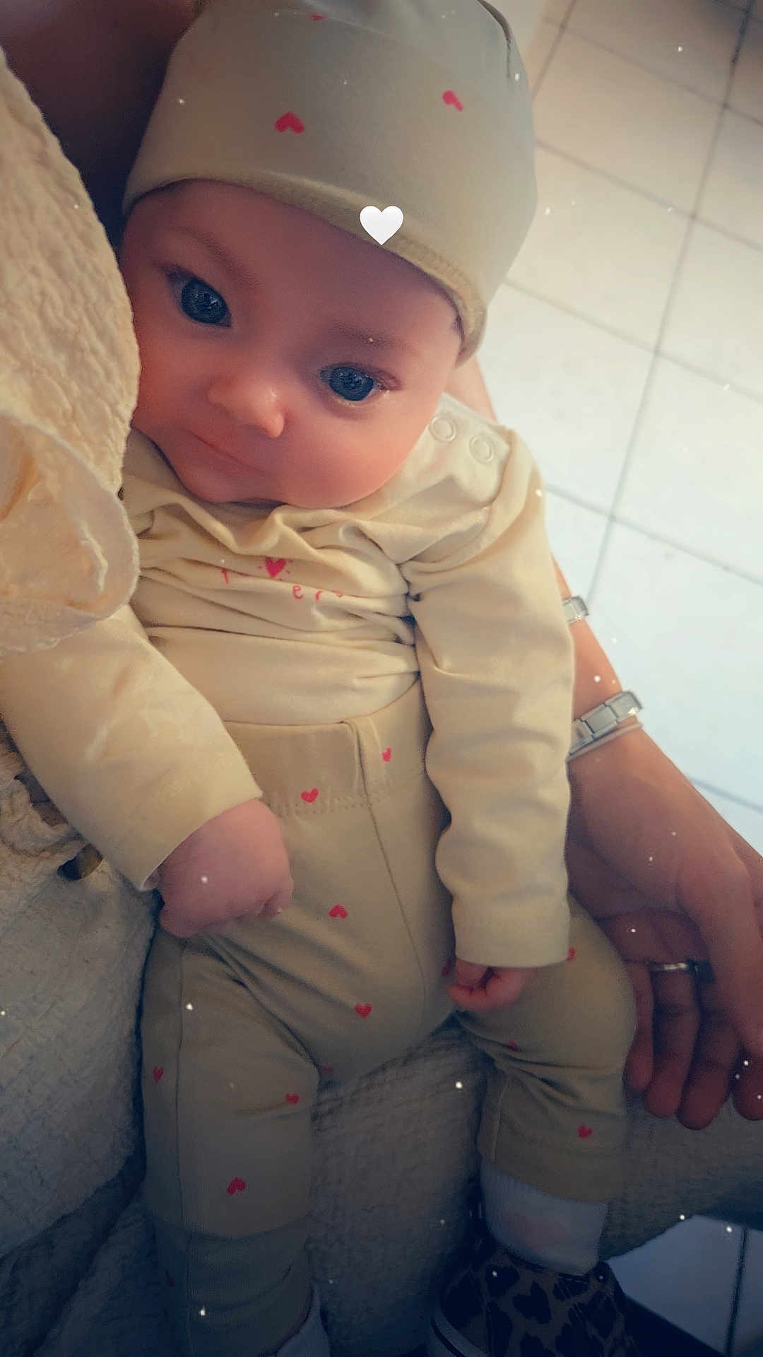 Yona participe au concours pour gagner de l'argent avec cette photo : baby, infant, child, hat, clothing, heart_pattern, hand, watch, floor_tiles, socks, shoes, couch, blanket, person, portrait, indoors, cute, soft_light, closeup, warm_tones