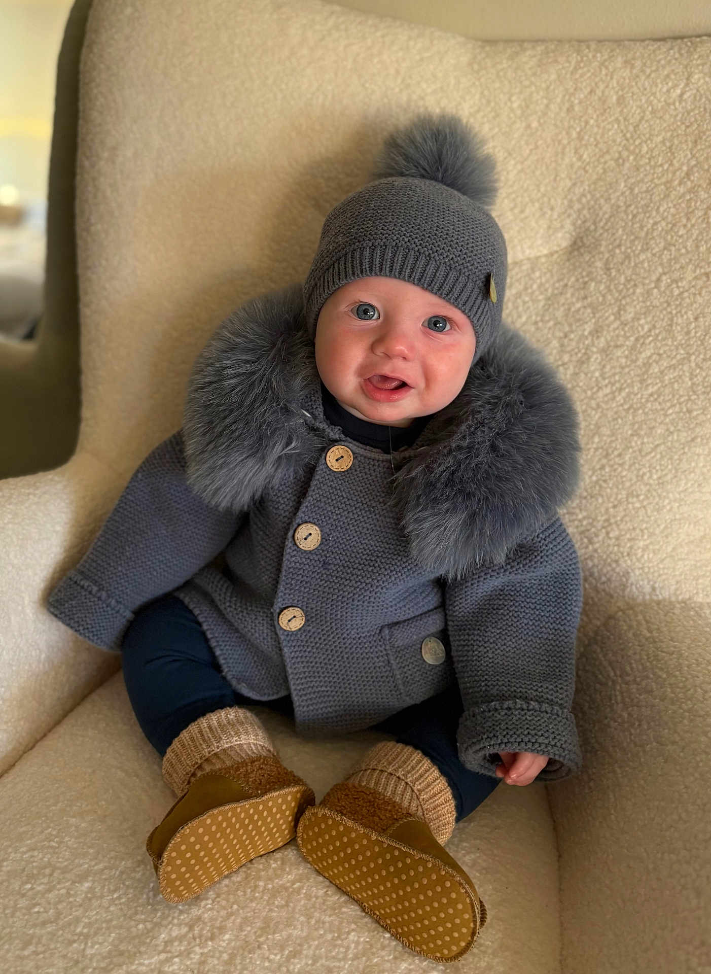 Mack joined the competition — help win amazing prizes! baby, child, knit_hat, pom_pom, gray_sweater, fur_trim, armchair, cozy, warm_clothing, sitting, cute, indoors, soft_texture, legs, baby_booties, smiling, happy, portrait, person, infant