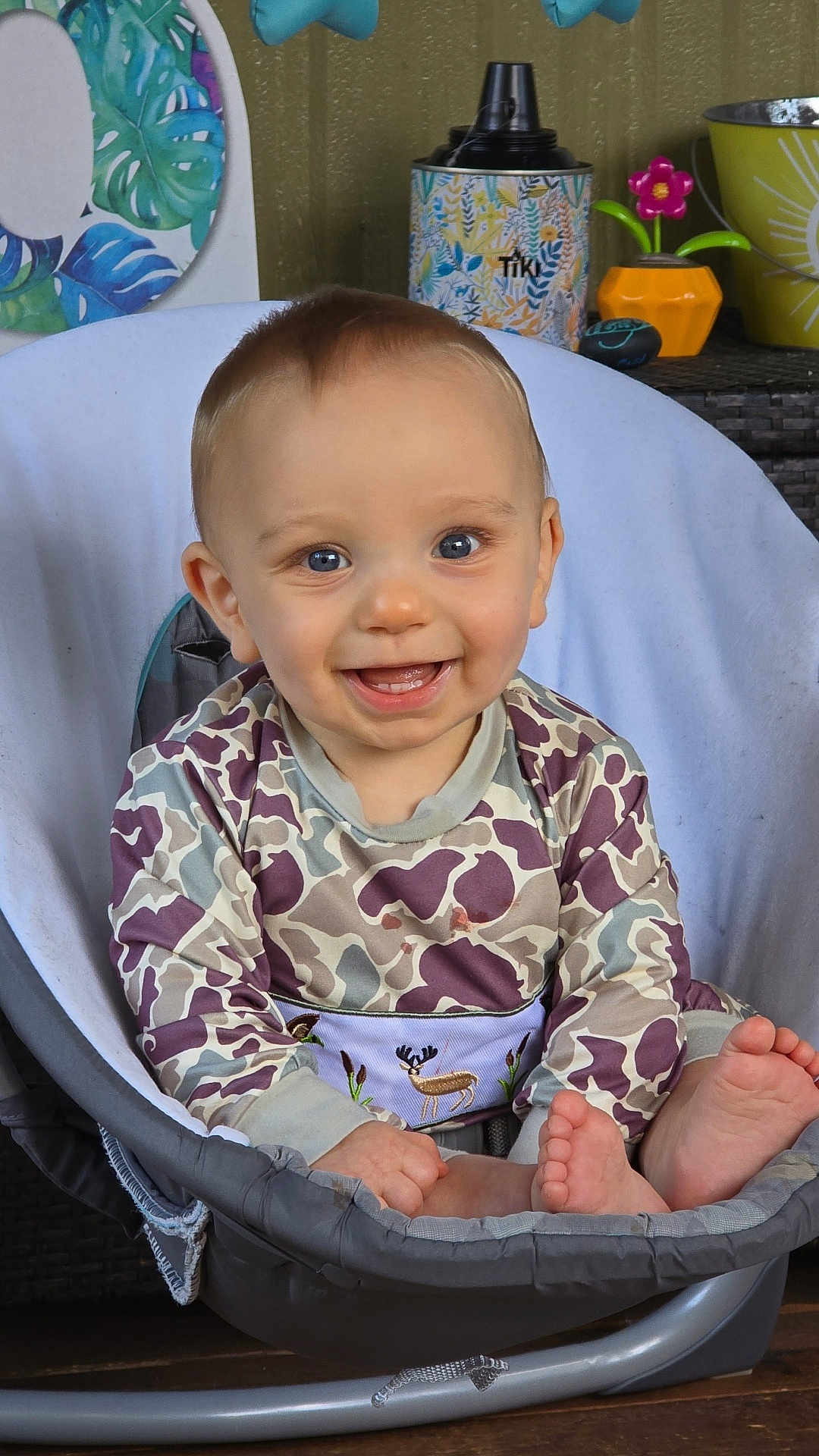 David is registered to the contest to win money with this photo: baby, child, smiling, blue_eyes, sitting, clothing, patterned_outfit, foot, chair, indoor, happy, face, young_child, cute, person, home, decor, colorful, toy, expression