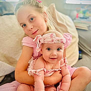 Mari is registered to the contest to win money with this photo: child, baby, girl, smiling, holding, pink_clothing, headband, indoor, couch, happy, family, portrait, cute, infant, sitting, love, together, home, soft_light, blurry_background