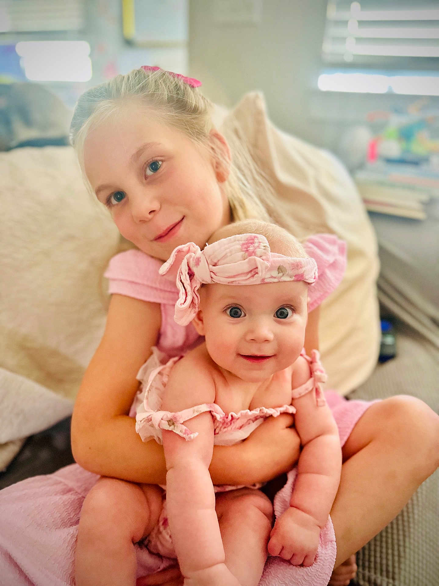 Mari is registered to the contest to win money with this photo: child, baby, girl, smiling, holding, pink_clothing, headband, indoor, couch, happy, family, portrait, cute, infant, sitting, love, together, home, soft_light, blurry_background