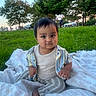 baby, child, grass, blanket, park, outdoor, trees, person, clothing, striped_pants, shirt, nature, sitting, portrait, daylight, greenery, relaxing, cute, infant, casual
