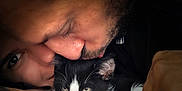 Hadès participe au concours pour gagner de l'argent avec cette photo : cat, black_and_white_cat, person, face, kiss, affection, close_up, tattoo, hand, ring, beard, eyelashes, fur, whiskers, indoor, cuddle, sleepy, relaxed, intimacy, portrait