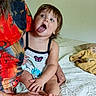 adult, bed, blanket, child, colorful_clothing, expression, face, hair, hand, holding, indoor, people, playful, portrait, room, sitting, skin, toddler, tongue, woman