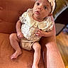 baby, infant, child, armchair, orange, clothing, headband, lace, buttons, fabric, sitting, indoors, skin, feet, legs, hand, face, eyes, expression, portrait