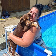 Bella participe au concours pour gagner de l'argent avec cette photo : woman, dog, hugging, pool, outdoor, sunny, smiling, pet, brown_dog, swimming_pool, rug, concrete, door, garden_tools, blue, summer, happy, tattoo, casual, relaxation