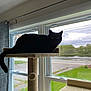 black_cat, cat_tree, window, indoor, pet, animal, feline, curtain, grass, outdoor_view, sky, cloudy, road, nature, tree, home, cozy, resting, domestic_cat, quiet