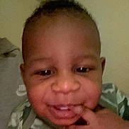 Oshian is registered to the contest to win money with this photo: child, toddler, face, smile, hand, camouflage, clothing, indoor, person, baby, skin, head, cheek, eyes, nose, mouth, fingers, expression, portrait, cute