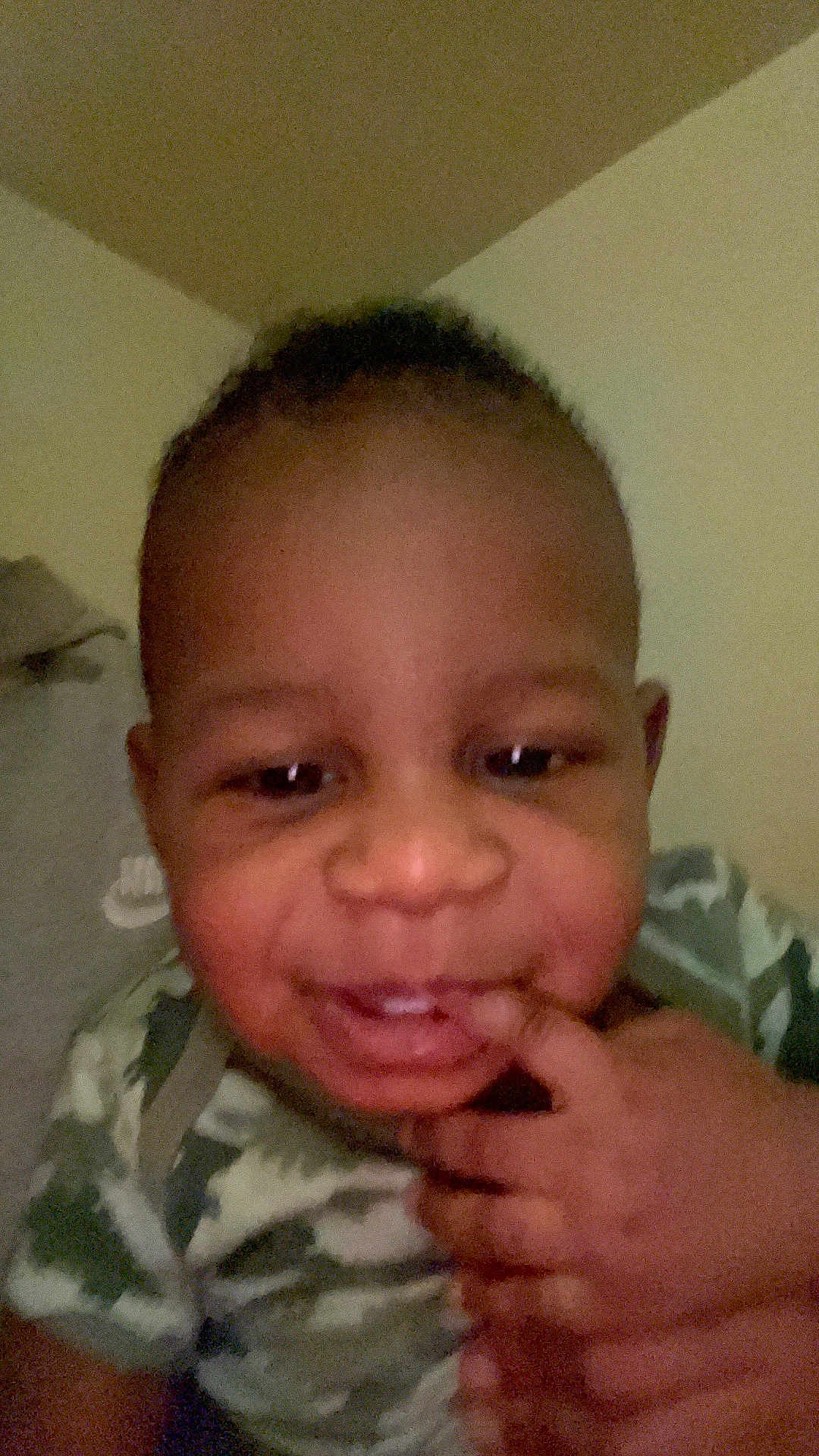 Oshian is registered to the contest to win money with this photo: child, toddler, face, smile, hand, camouflage, clothing, indoor, person, baby, skin, head, cheek, eyes, nose, mouth, fingers, expression, portrait, cute