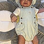baby, infant, child, romper, hat, striped_clothing, soft_cushion, flower_shape, lying_down, alert, wide_eyes, skin, arm, leg, baby_clothes, cozy, indoor, person, newborn, cute