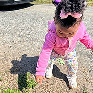 Lolani Davenport is registered to the contest to win money with this photo: car, casual_clothing, child, colorful_pants, curious, grass, hair_bows, nature, outdoor, pacifier, pink_hoodie, playing, pointing, shadow, shoes, sidewalk, standing, sunny_day, toddler, young_child