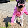 car, casual_clothing, child, colorful_pants, curious, grass, hair_bows, nature, outdoor, pacifier, pink_hoodie, playing, pointing, shadow, shoes, sidewalk, standing, sunny_day, toddler, young_child