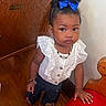 Lolani Davenport is registered to the contest to win money with this photo: blue_bow, bracelet, child, curly_hair, cute, expression, footwear, girl, hand_on_bench, indoor, lace, navy_pants, necklace, portrait, red_cushion, standing, toddler, white_top, wooden_bench, wooden_floor