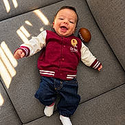 Elias joined the competition — help win amazing prizes! baby, child, smiling, happy, portrait, indoors, sofa, couch, football, sportswear, varsity_jacket, jeans, socks, lying_down, sunlight, natural_light, face, infant, clothing, playful