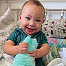 baby, blue_eyes, smiling, toy, fluffy, indoor, child, cute, happy, portrait, bed, blanket, colorful, couch, infant, person, clothing, hand, face, soft