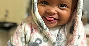 Zaylah joined the competition — help win amazing prizes! baby, babylaughing, blanket, bonnet, clothing, coat, face, happy, hat, head, hood, hoodie, jacket, knitwear, laughing, person, photography, portrait, sitting, smile