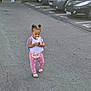 toddler, child, outdoor, parking_lot, asphalt, car, pacifier, purse, pink_pants, tank_top, hair_buns, toy, footwear, sandals, vehicle, sidewalk, daytime, person, young_child, curious