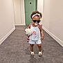 toddler, child, sunglasses, pacifier, plush_toy, hallway, white_clothing, headband, sandals, carpet, door, wall, floor, cute, walking, indoor, person, baby, fashion, cool