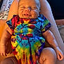 Charlie joined the competition — help win amazing prizes! baby, smiling, tie_dye, onesie, infant, legs, arms, person, sitting, indoor, carpet, furniture, skin, happy, cute, child, relaxed, colorful, human, portrait