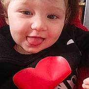 Léonie a rejoint le concours — aidez-le/la à gagner de superbes lots ! baby, black_shirt, child, closeup, cute, face, hair, hand, happy, indoor, person, portrait, red_heart, skin, smiling, sweater, toddler, tongue, warm_colors, young