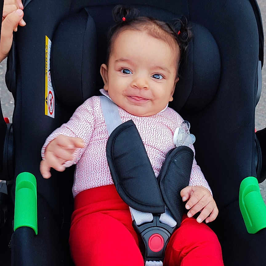 Talya a rejoint le concours — aidez-le/la à gagner de superbes lots ! baby, bright_clothing, car_seat, child, cute, hair_pigtails, happy, infant, outdoor, person, playful, red_pants, safety_harness, seatbelt, sidewalk, small_hands, smiling, stroller, toddler, white_socks