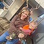 Hadley is registered to the contest to win money with this photo: woman, child, toddler, antlers, face_paint, outdoor, porch, wooden_deck, casual_clothing, camo_pants, orange_vest, pacifier, smile, playful, family, daylight, jeans, holding, fun, person
